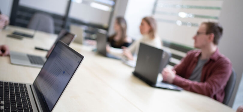 work team at a meeting with laptops on desks